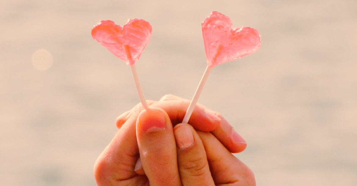 hands holding two heart lollipops