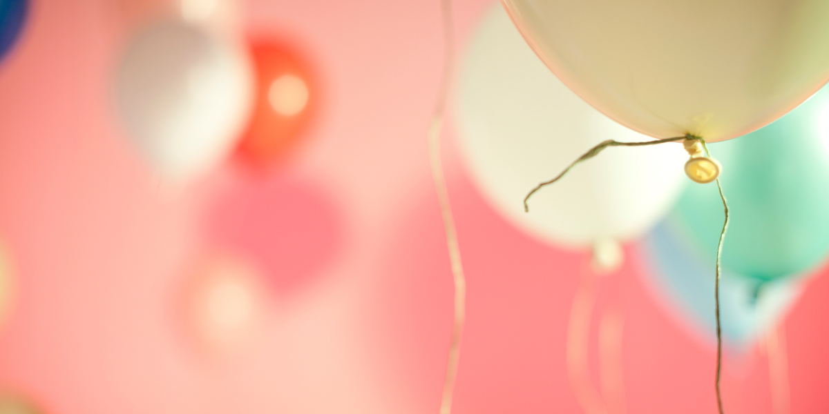 A variety of pastel colored balloons in a room that is a pale pink.